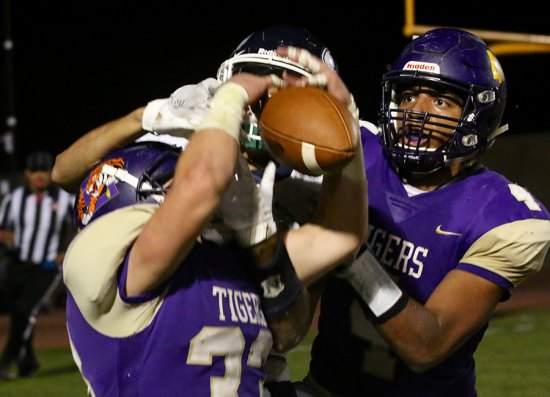 Lemoore's William Kloster (33) and Elijah Jones (4) battle Redwood player for the ball in the end zone.